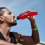 man drinking electrolyte drink from bottle after workout for hydration