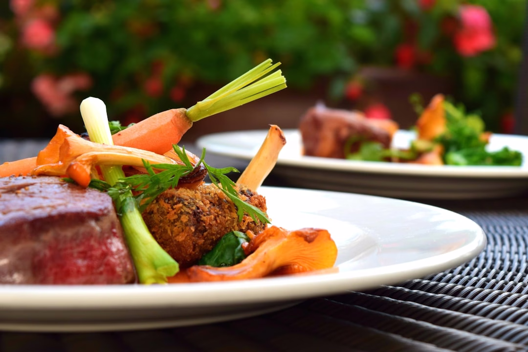 Grilled steak served with carrots, celery, and fresh vegetables on a plate, representing a paleo-style whole food meal