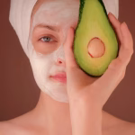 Woman wearing a face mask holding an avocado while illustrating acne diet myths