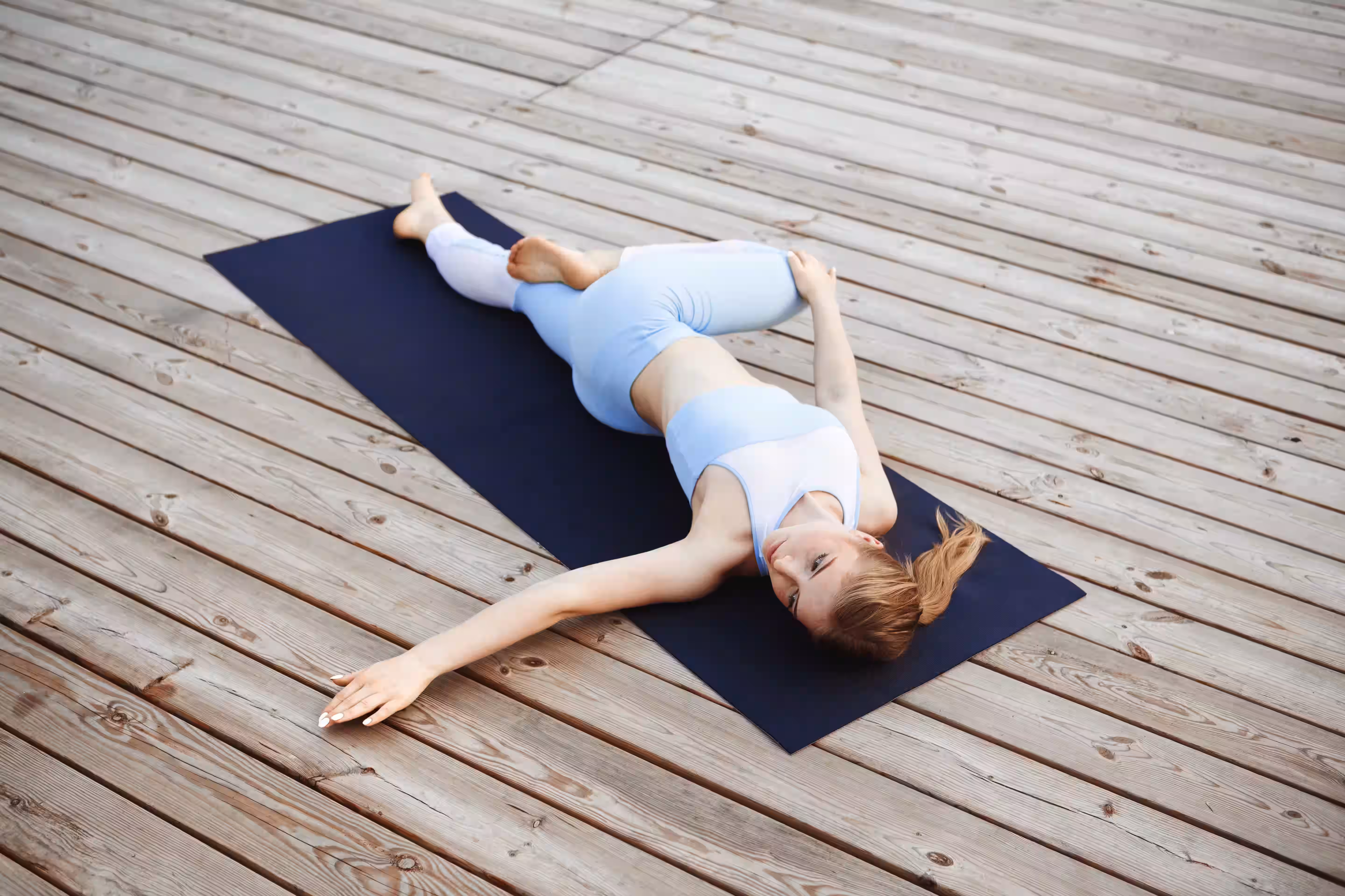 Woman practicing Supine Twist yoga pose