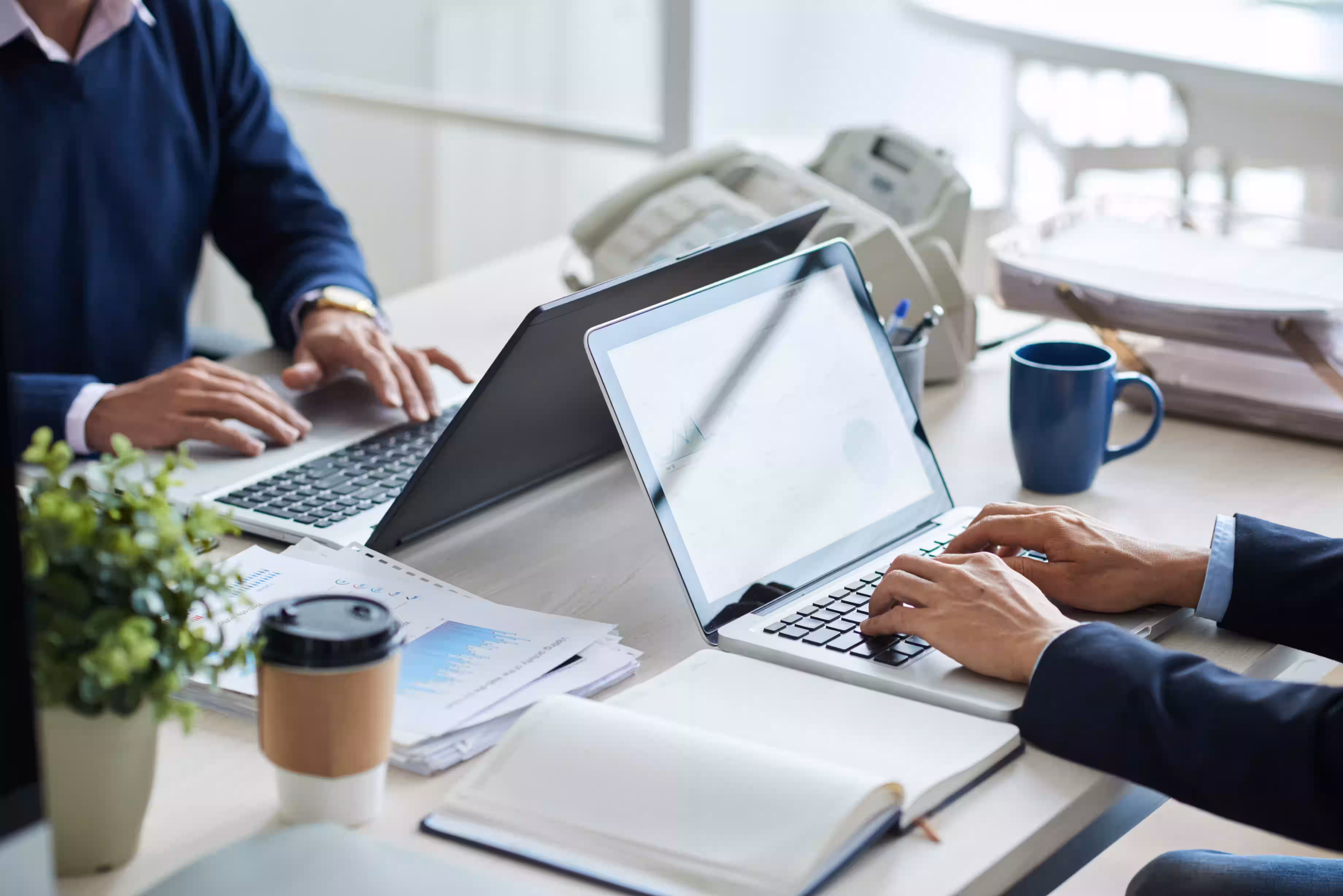 two people working on laptops in a clean and modern workspace