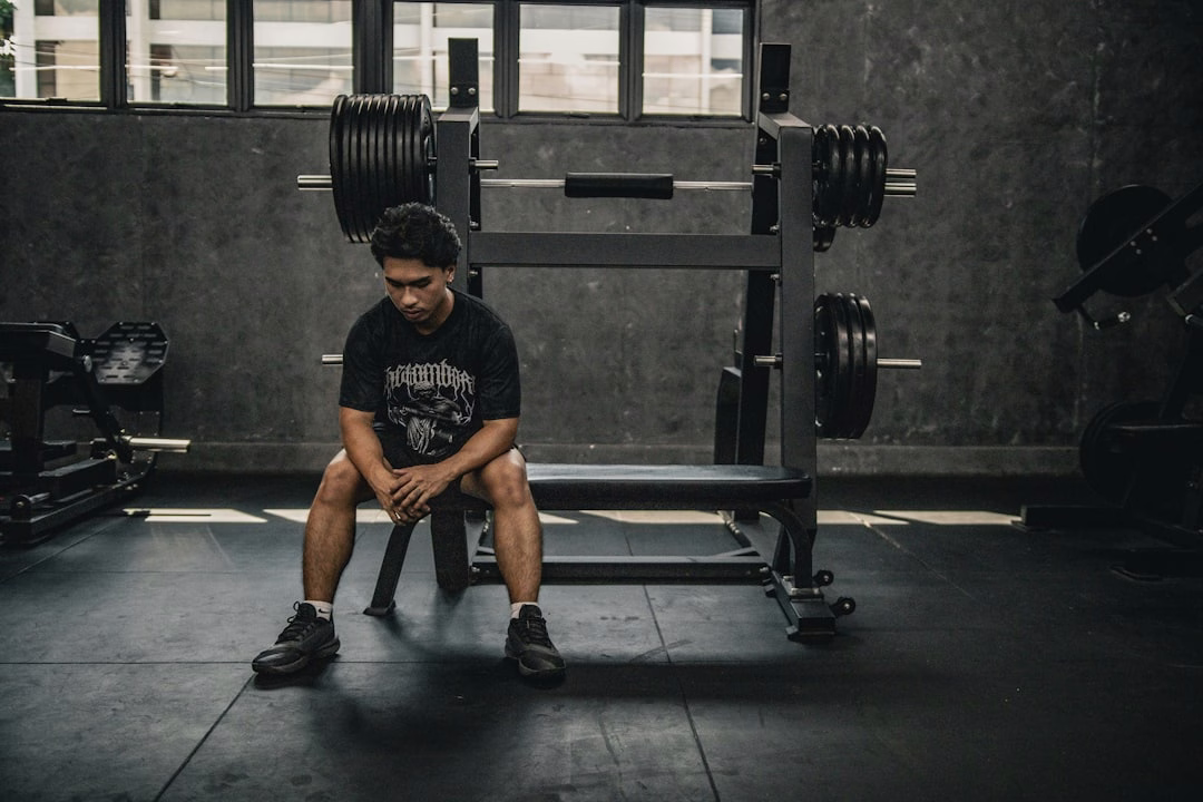Man sitting in a gym looking thoughtful, reflecting on muscle building tips and workout mistakes