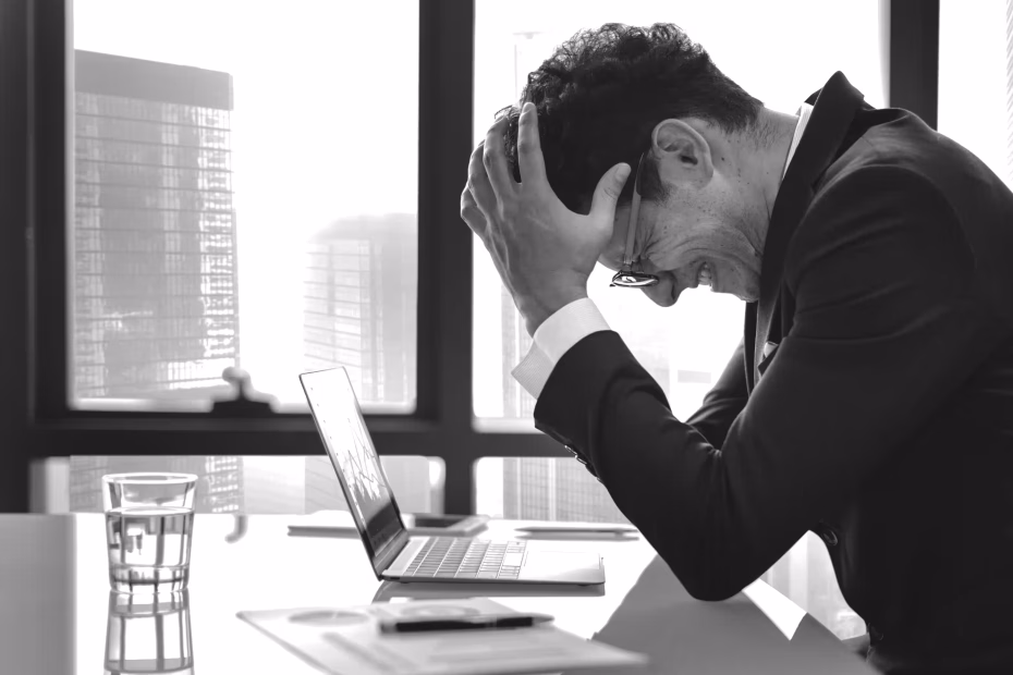 Man experiencing stress and burnout resting his head on a desk in a workplace setting, showing emotional exhaustion and mental fatigue