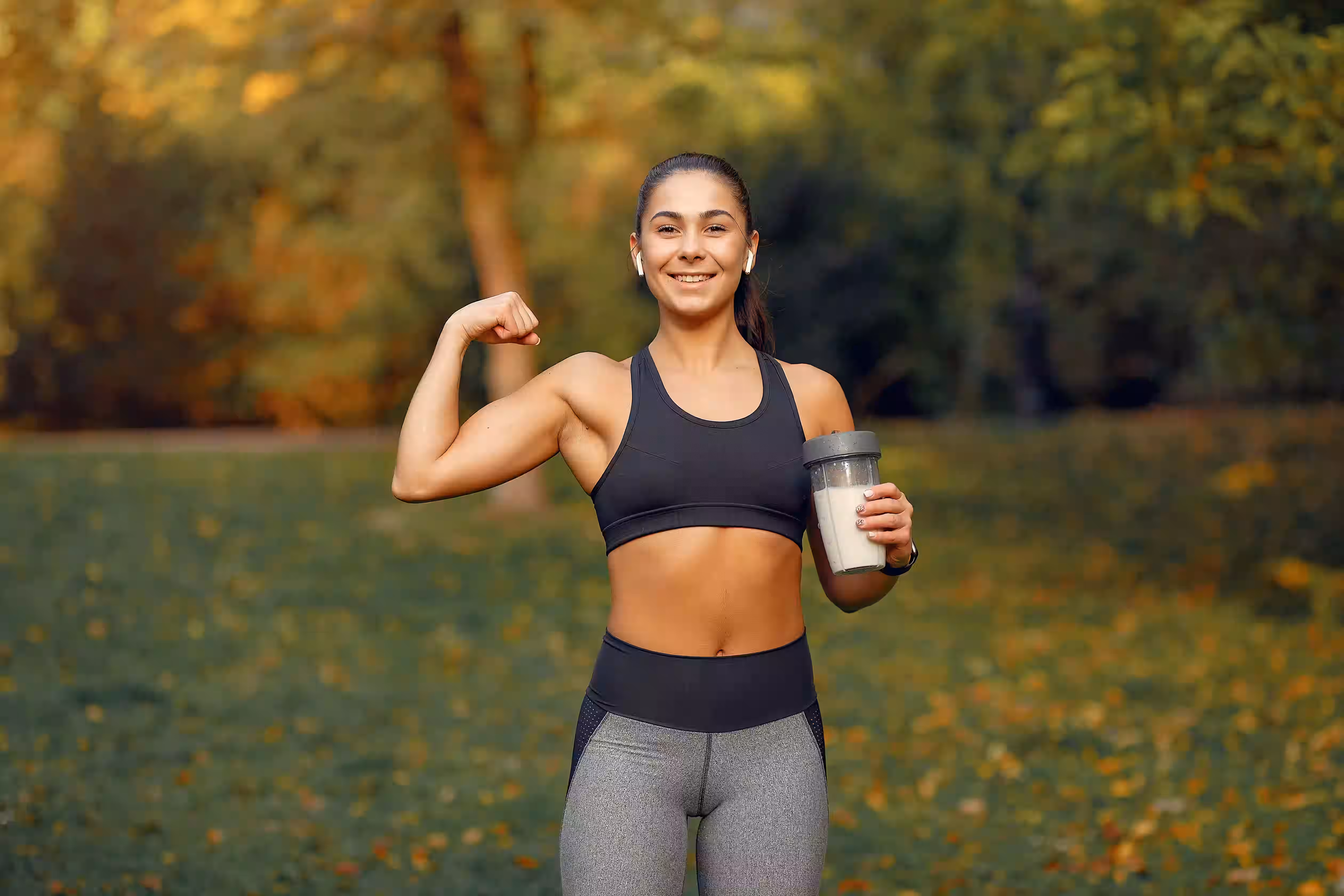 Fit woman holding a shaker bottle outdoors, representing creatine for women and active wellness
